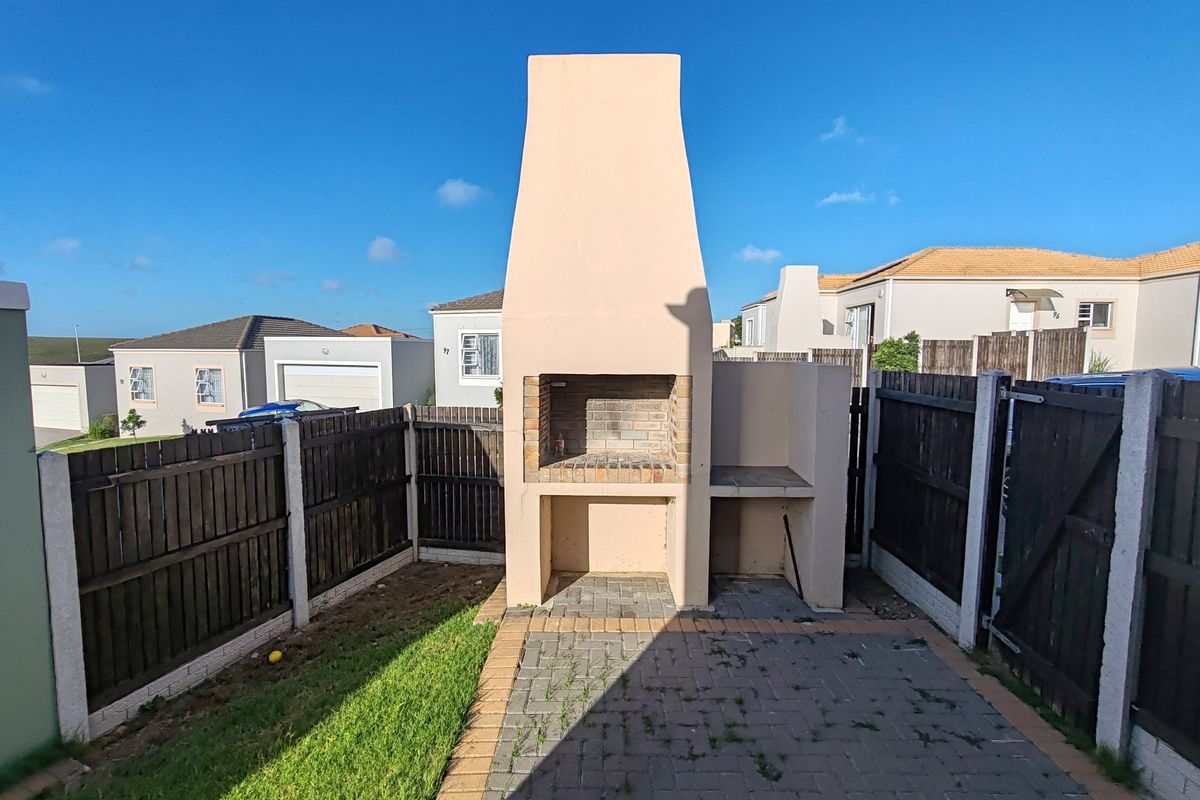 A private rear courtyard featuring a built-in brick braai, paved patio area, and enclosed timber fencing.