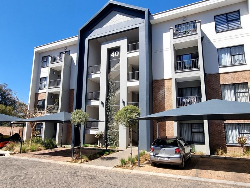 Front elevation of a modern multi-story apartment complex featuring brick and render finishes, private balconies, and dedicated shade-cloth covered parking bays.