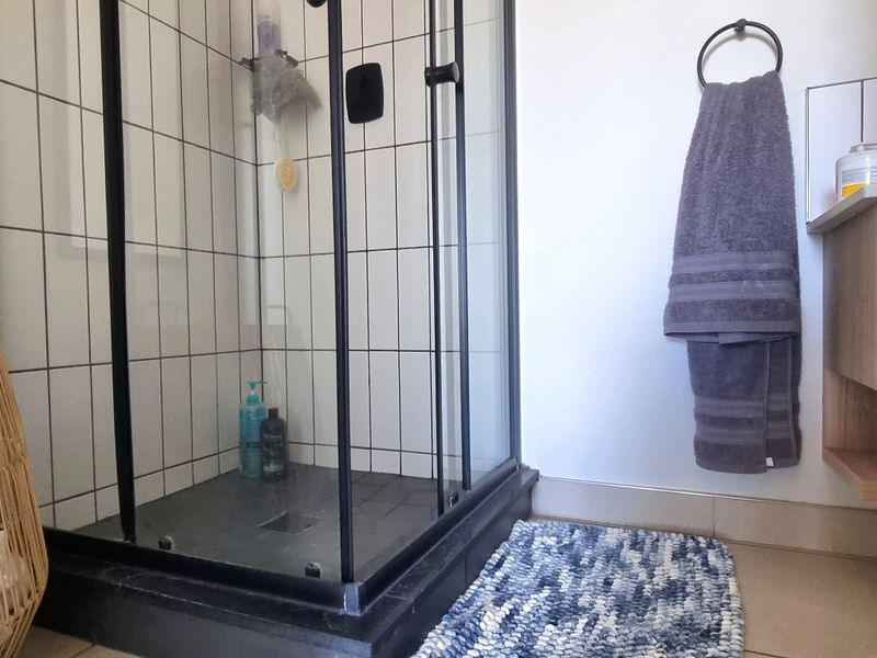 Modern bathroom featuring a black-framed glass shower enclosure, tiled walls, and a contemporary floating vanity with a vessel sink.