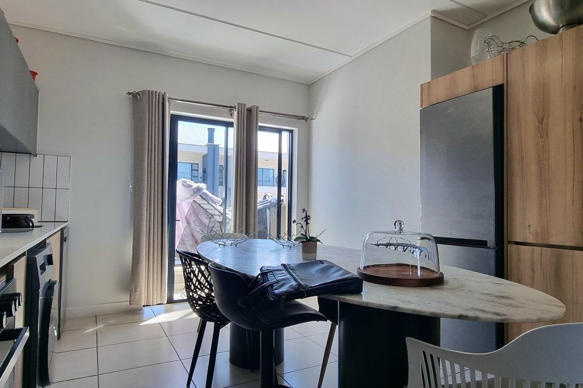 Modern kitchen featuring built-in cabinetry, integrated appliances, and tiled flooring, with direct access to an outdoor area through a sliding glass door.
