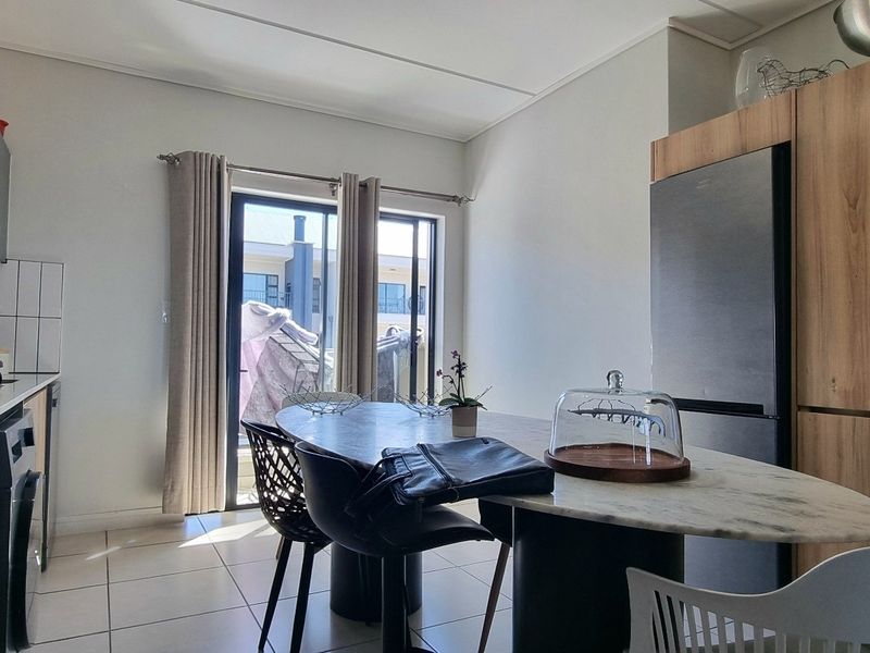 Modern kitchen featuring built-in cabinetry, integrated appliances, and tiled flooring, with direct access to an outdoor area through a sliding glass door.
