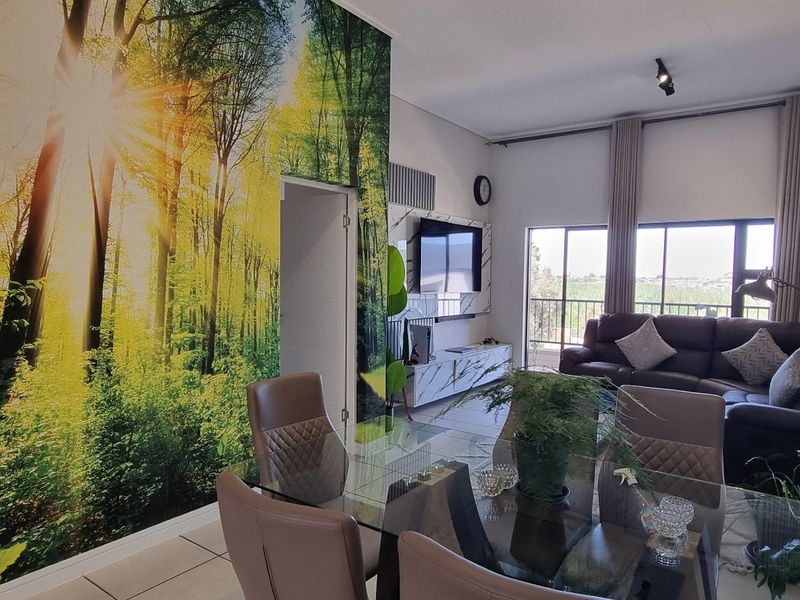 Open-plan living and dining area featuring tiled floors, a built-in media unit, and large sliding doors leading to an outdoor space.