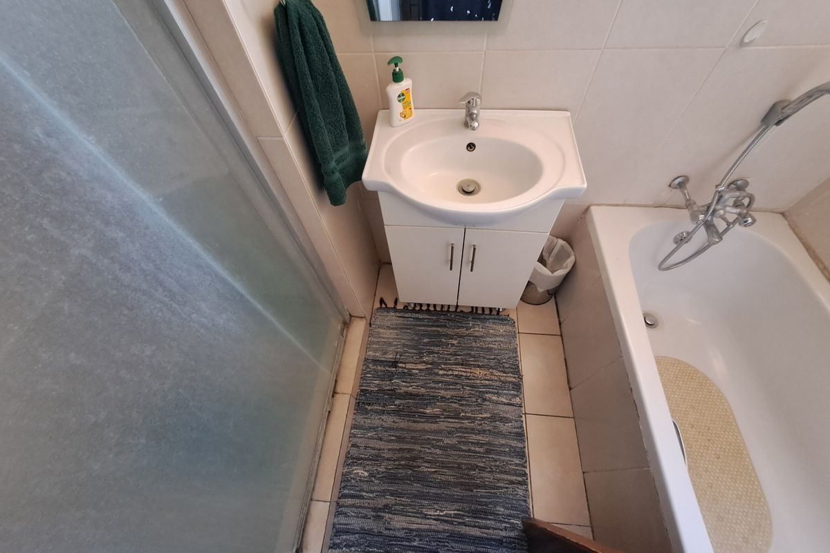 Compact bathroom featuring a vanity basin, shower enclosure, and bathtub with neutral wall tiling.