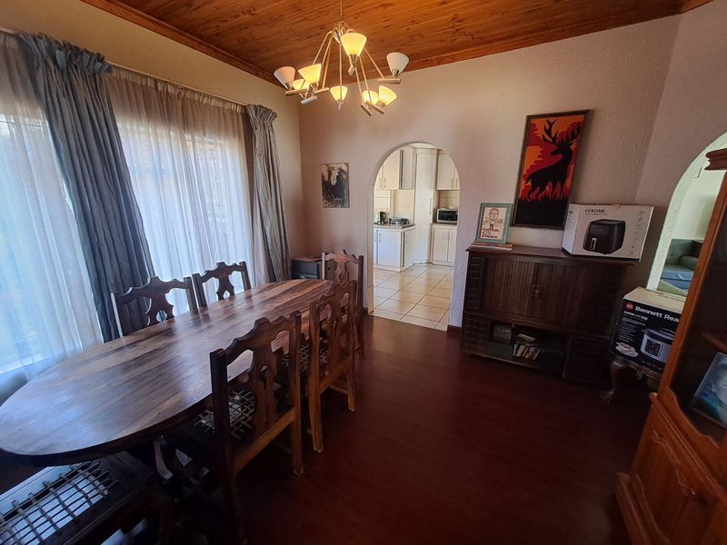 Dining room featuring a timber ceiling, laminate flooring, and an arched doorway leading to the kitchen area.