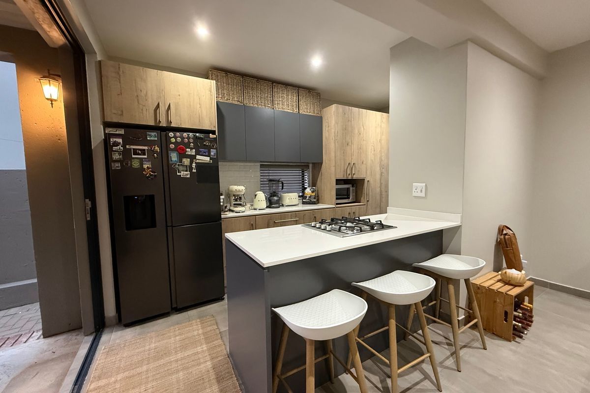 Modern kitchen featuring two-tone cabinetry, stone countertops, a gas cooktop on the breakfast island, and direct access to an outdoor area.