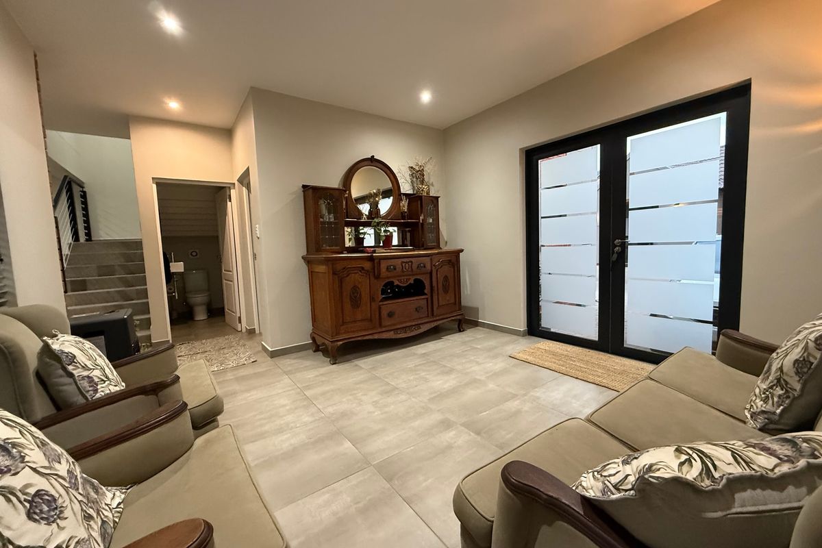 A well-maintained living area featuring large format floor tiles, recessed lighting, and double glass doors leading to an outdoor space.