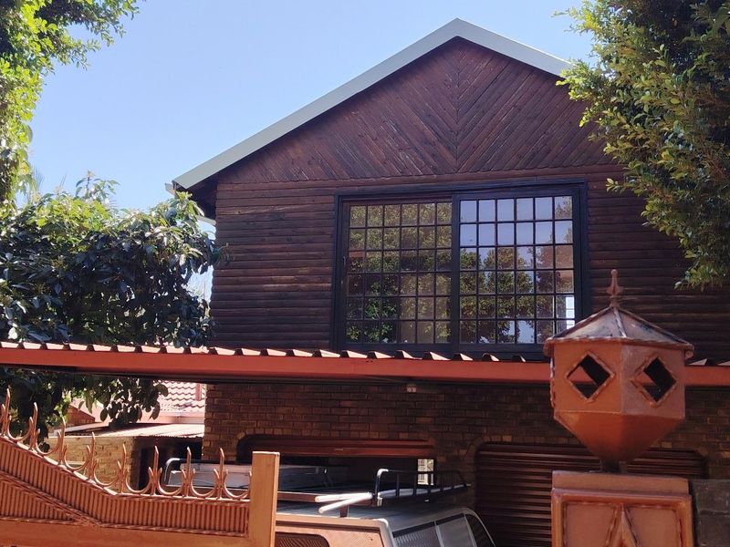 Front view of a two-story house featuring timber cladding, brick lower level, and a covered carport area.