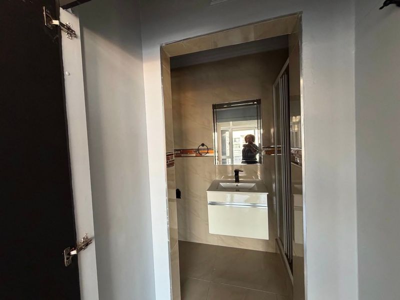 A modern bathroom featuring a wall-mounted vanity with a basin, tiled walls, and a glass shower enclosure.