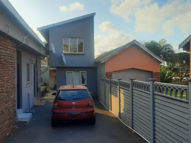 Front exterior view of the property featuring a driveway, garage, and boundary walling.