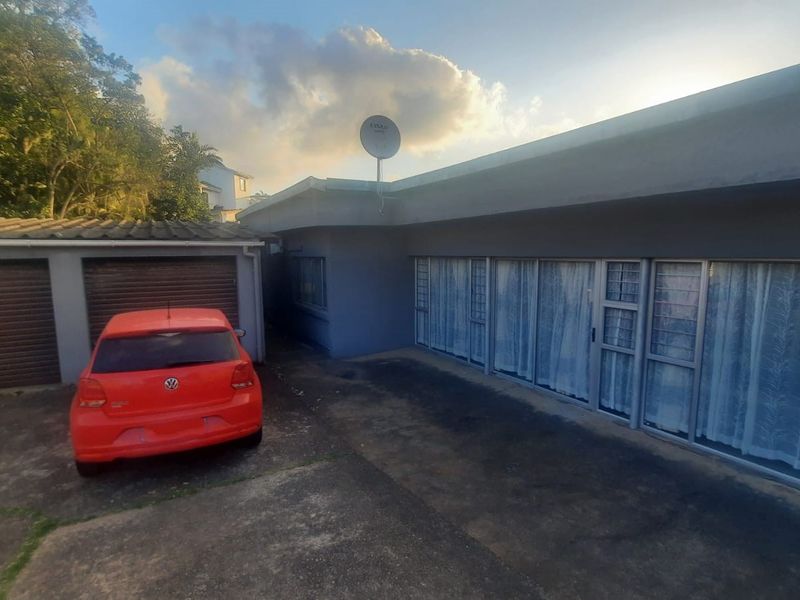 Front exterior view of the property featuring a double garage, concrete driveway, and large aluminium sliding doors providing access to the home.