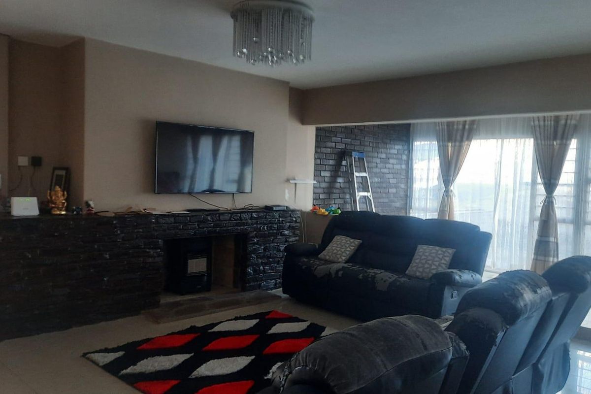 Spacious living room featuring a dark brick fireplace, tiled flooring, and large sliding glass doors that provide ample natural light.