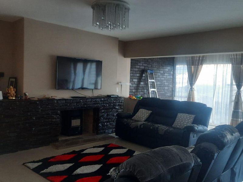 Spacious living room featuring a dark brick fireplace, tiled flooring, and large sliding glass doors that provide ample natural light.