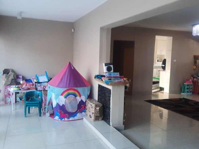Open plan living area featuring tiled flooring and a central partition wall, providing a versatile space that flows into the adjacent kitchen area.