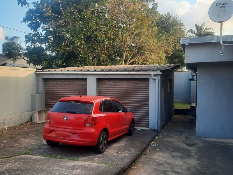 Exterior view of a double garage featuring roller shutter doors and a concrete driveway area.