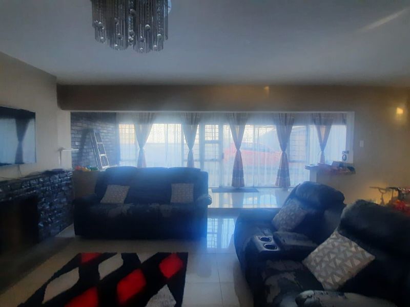 Spacious living room featuring tiled flooring, a stone-clad fireplace, and large sliding glass doors that provide ample natural light.
