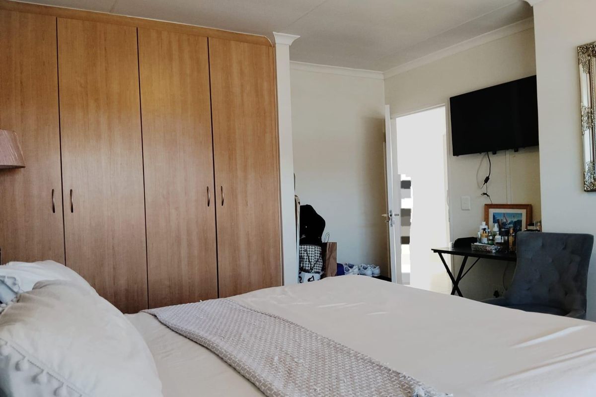 A bedroom featuring built-in wooden cupboards, coving, and a wall-mounted television, offering a functional and comfortable living space.