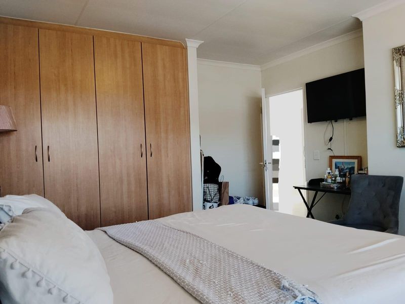 A bedroom featuring built-in wooden cupboards, coving, and a wall-mounted television, offering a functional and comfortable living space.