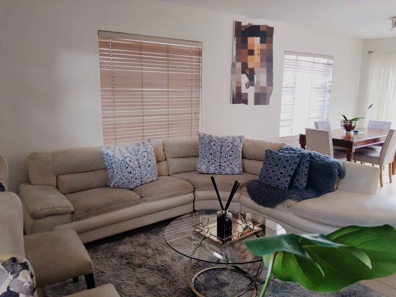 An open-plan living and dining area featuring neutral tiled flooring and venetian blinds, providing a bright and functional space for relaxation and meals.