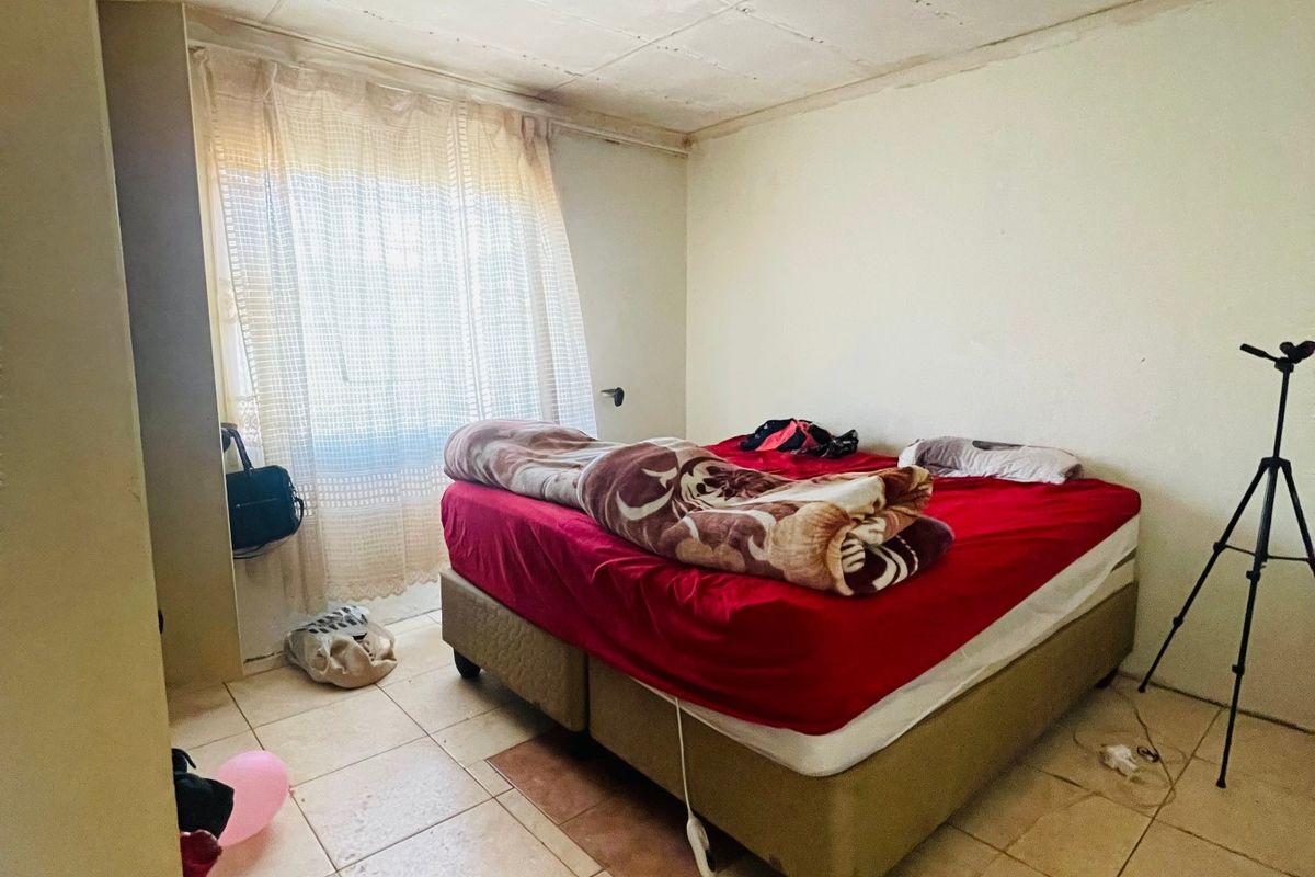 A bedroom featuring tiled flooring and a basic ceiling finish, requiring cosmetic updates to improve the overall aesthetic and condition of the space.