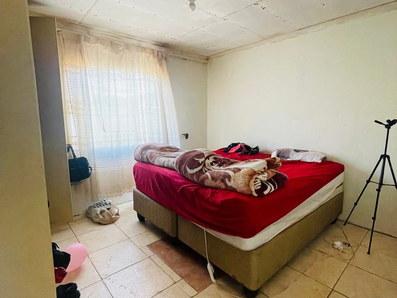 A bedroom featuring tiled flooring and a basic ceiling finish, requiring cosmetic updates to improve the overall aesthetic and condition of the space.
