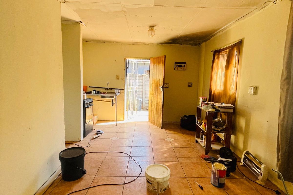 A dated kitchen area featuring tiled flooring and basic fixtures, currently in need of significant renovation and cosmetic repairs to the ceiling and walls.