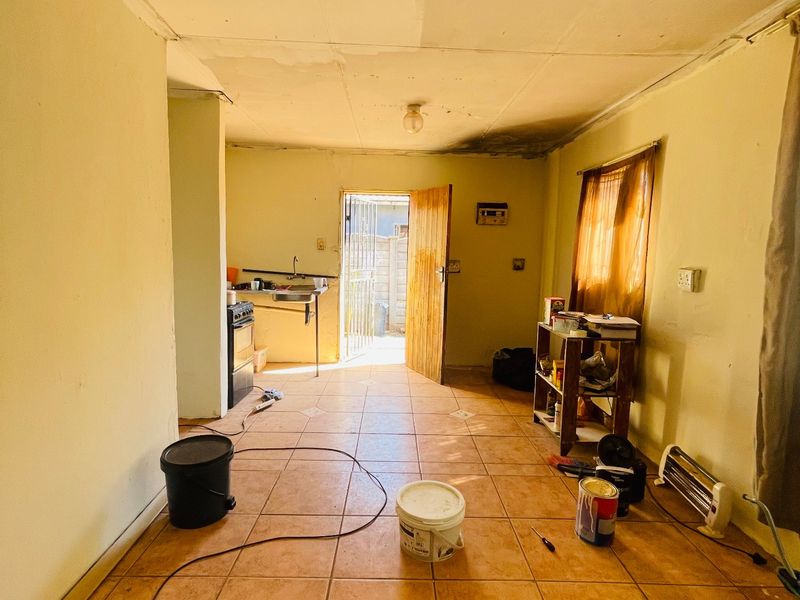 A dated kitchen area featuring tiled flooring and basic fixtures, currently in need of significant renovation and cosmetic repairs to the ceiling and walls.