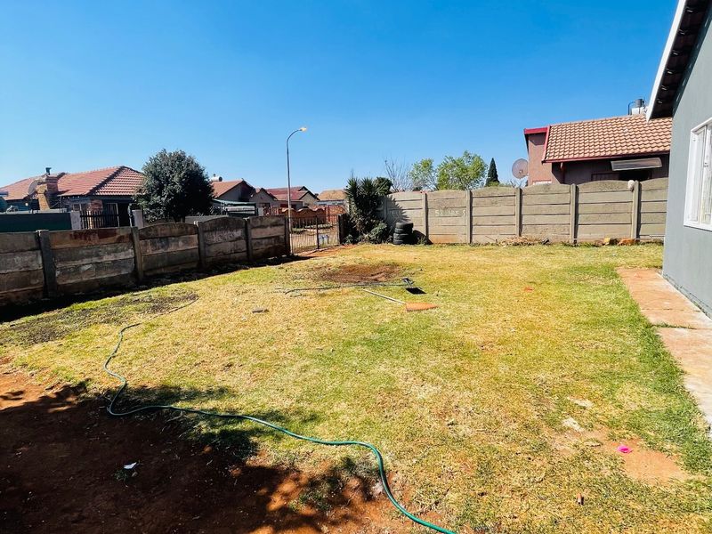 A rear garden area featuring a lawn and precast concrete boundary walls, offering potential for landscaping and outdoor improvement.