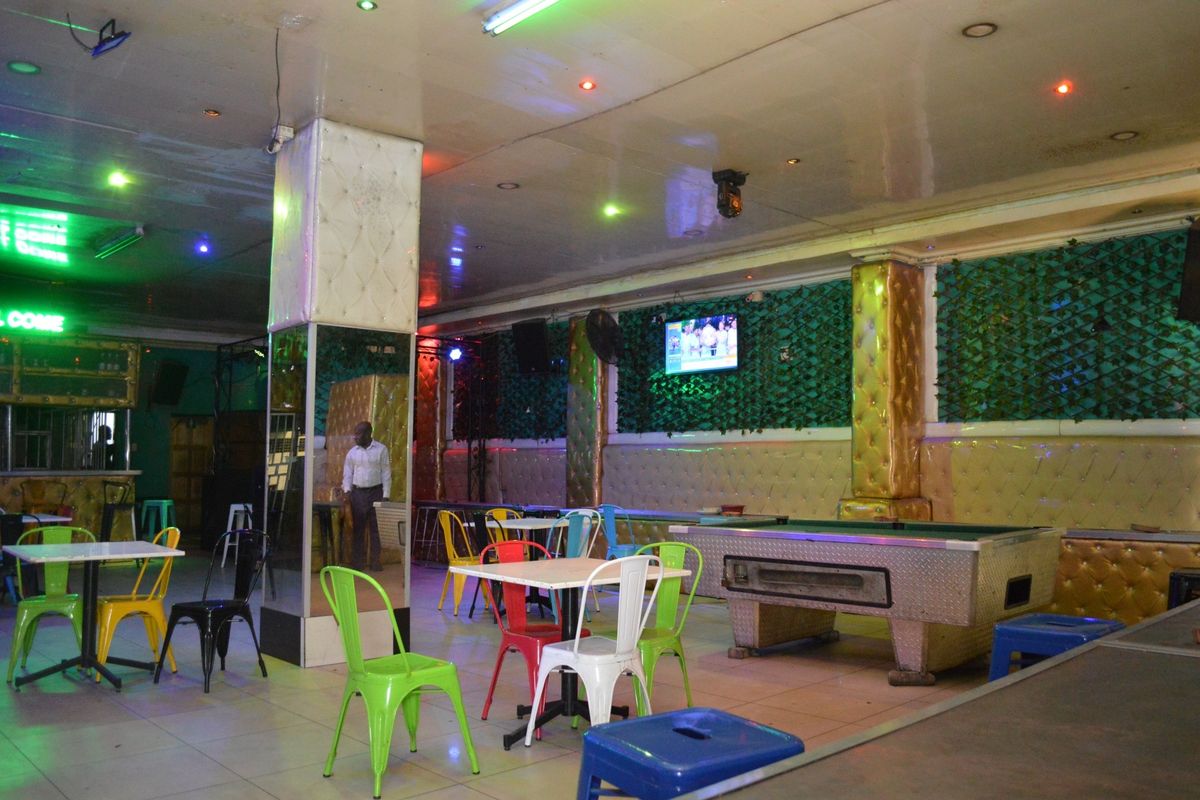 Spacious commercial bar area featuring tiled flooring, mirrored columns, and decorative upholstered wall paneling with integrated lighting.
