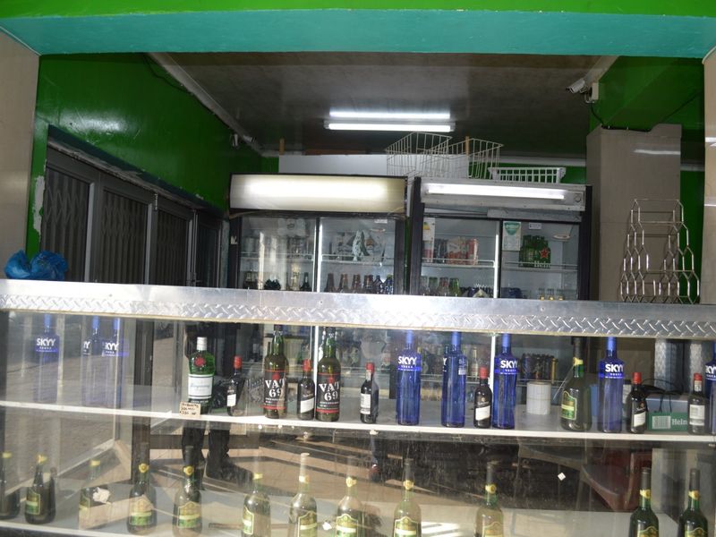 Commercial bar area featuring a glass display counter, built-in commercial refrigeration units, and overhead fluorescent lighting.