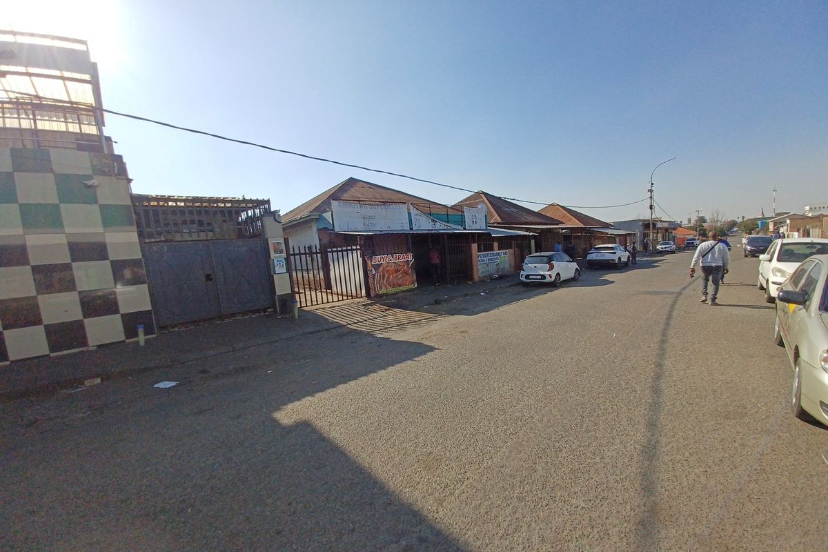 Street view of a commercial property featuring a tiled facade, metal security gate, and direct access to the main road.
