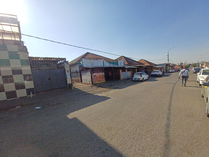 Street view of a commercial property featuring a tiled facade, metal security gate, and direct access to the main road.