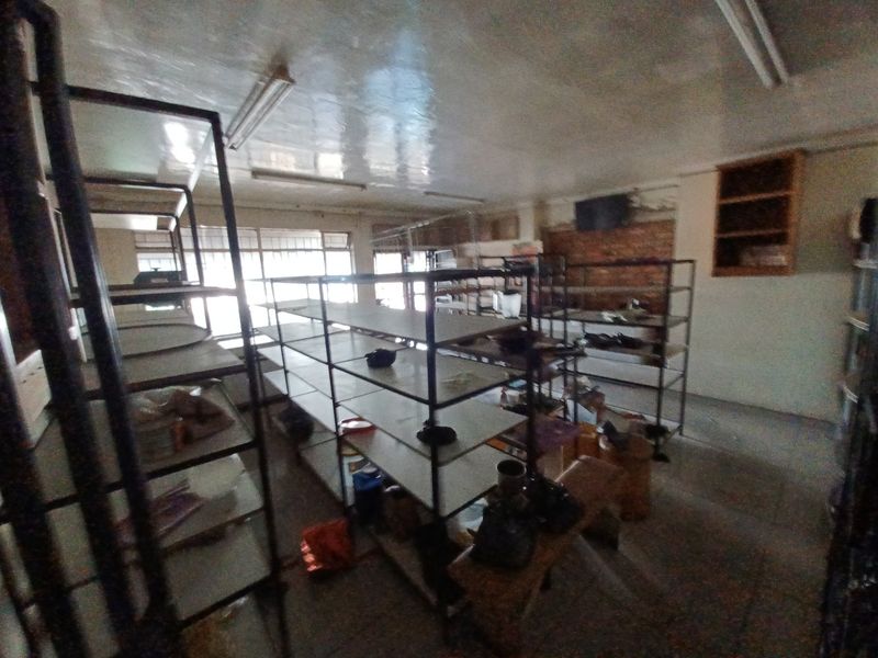 A utility or storage space featuring tiled floors, built-in shelving units, and exposed brickwork, currently in need of cosmetic refurbishment.