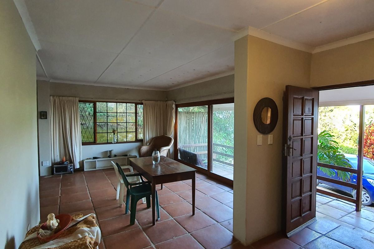 Spacious living area featuring terracotta floor tiles, large windows, and sliding glass doors providing direct access to the outdoor patio area.