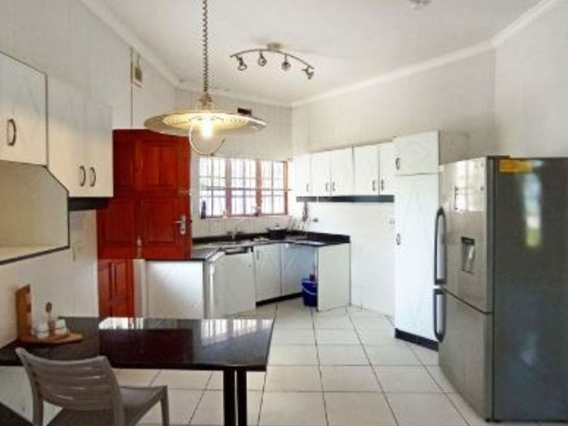 A functional kitchen featuring white built-in cabinetry, tiled flooring, and a breakfast nook area with pendant lighting.