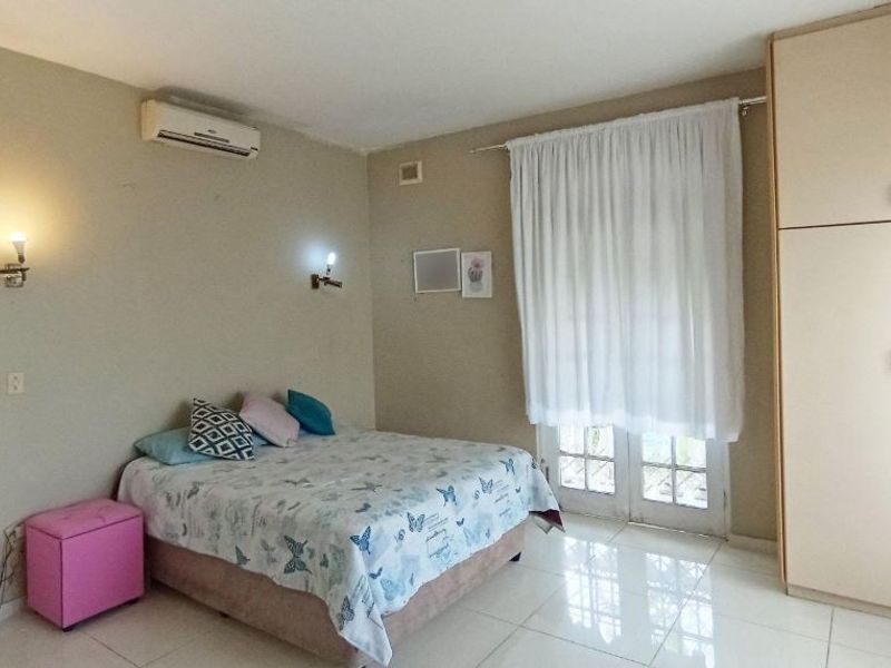 A bedroom featuring tiled flooring, built-in cupboards, wall-mounted lighting, an air conditioning unit, and access to the outdoors via french doors.