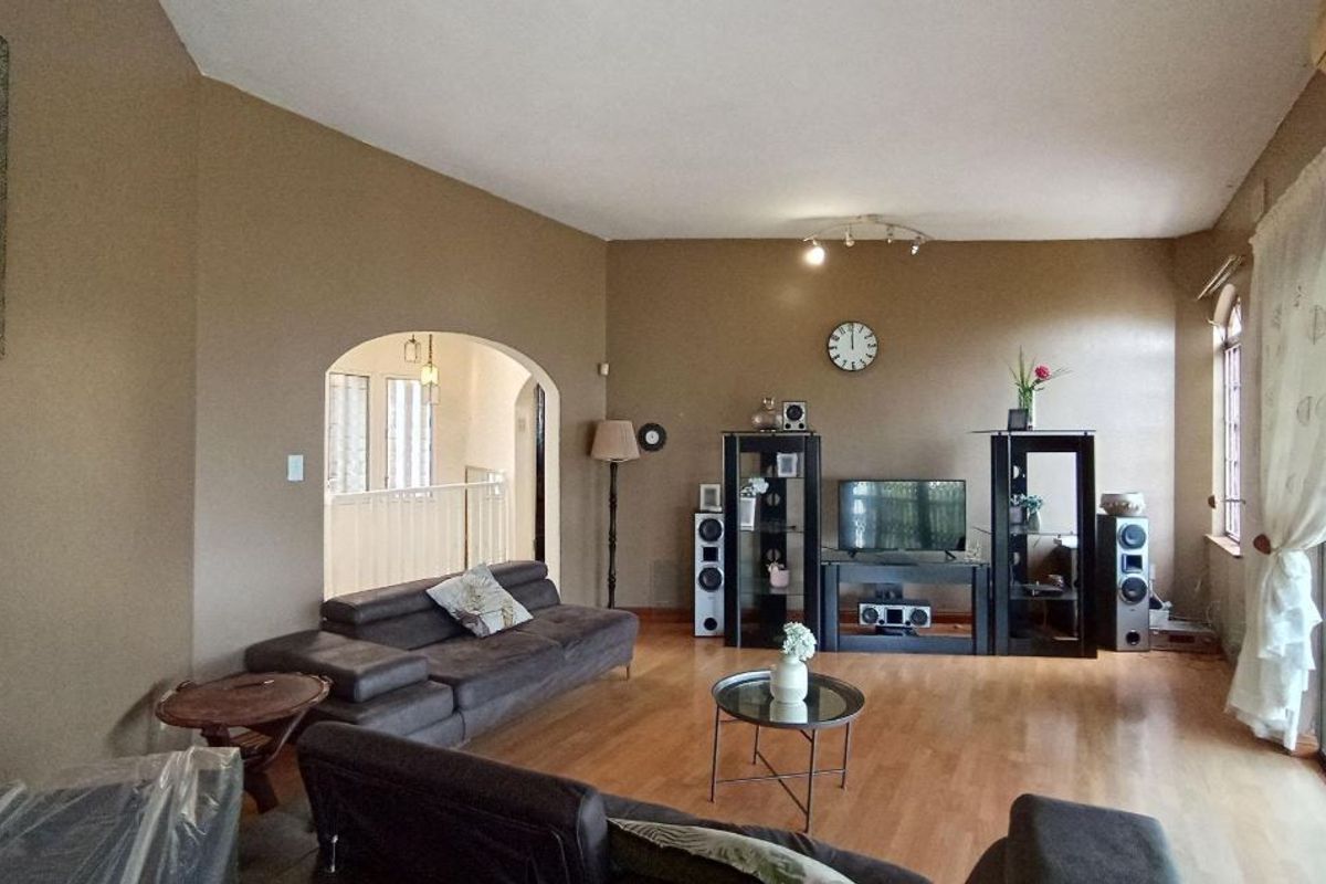 Spacious living room featuring laminate flooring, an arched entryway, and large sliding glass doors providing access to the exterior.