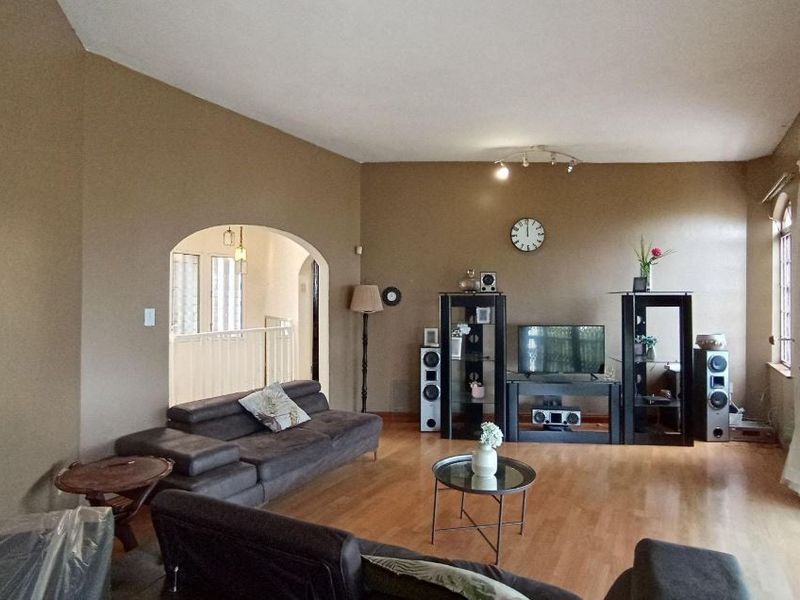 Spacious living room featuring laminate flooring, an arched entryway, and large sliding glass doors providing access to the exterior.