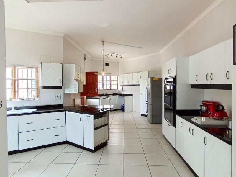 Spacious kitchen featuring white cabinetry, black granite countertops, integrated double wall oven, and tiled flooring throughout.