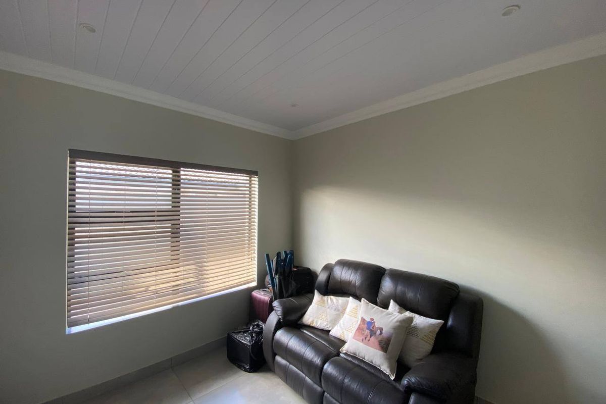 A living room featuring tiled flooring, a tongue and groove ceiling with recessed lighting, and fitted venetian blinds.