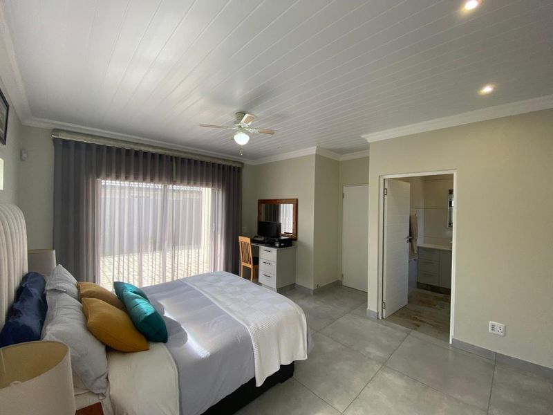 Spacious bedroom featuring tiled flooring, a ceiling fan, recessed lighting, and direct access to an en-suite bathroom through a standard doorway.