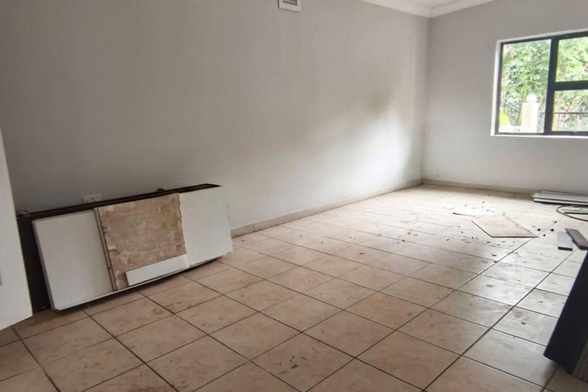 An empty bedroom featuring tiled flooring and an aluminium window frame, requiring cleaning and minor cosmetic updates to enhance its appeal.