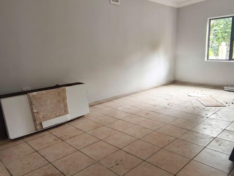 An empty bedroom featuring tiled flooring and an aluminium window frame, requiring cleaning and minor cosmetic updates to enhance its appeal.