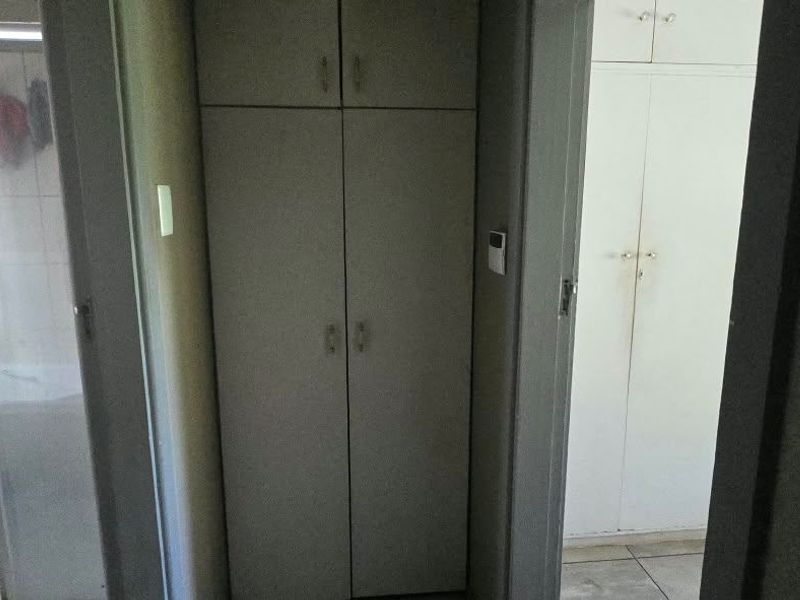 A functional hallway featuring built-in storage cupboards and direct access to an adjacent bathroom with a shower enclosure.