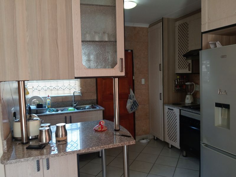 A functional kitchen featuring laminate cabinetry, granite countertops, tiled flooring, and built-in appliances including an oven and extractor fan.