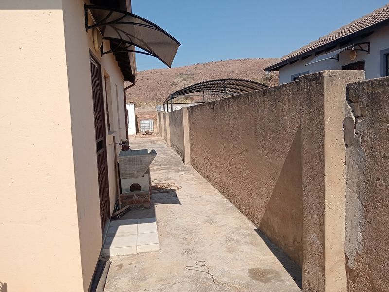 A narrow rear exterior walkway featuring a concrete boundary wall, a utility sink, and a protective door awning.