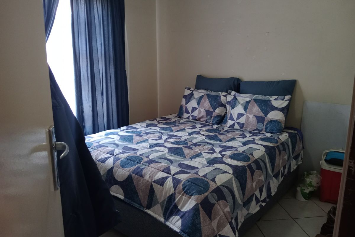 A compact bedroom featuring tiled flooring and neutral wall finishes, providing a functional space for rest.