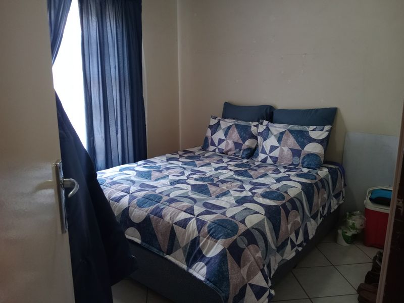 A compact bedroom featuring tiled flooring and neutral wall finishes, providing a functional space for rest.