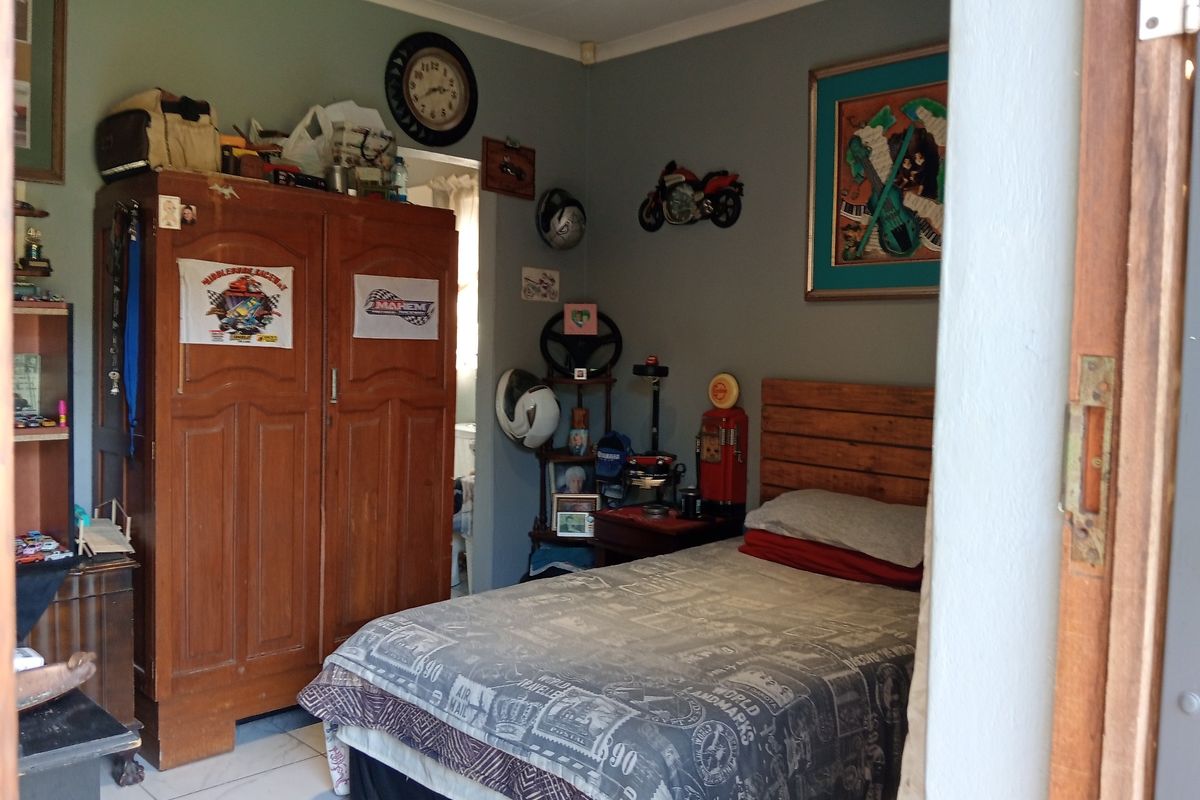 A bedroom featuring tiled flooring and a wooden door frame, providing a functional space for rest.