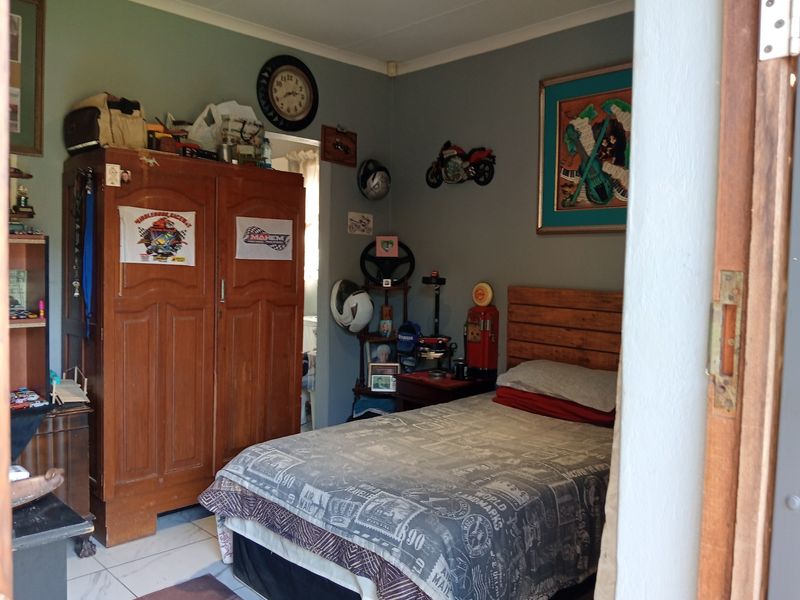 A bedroom featuring tiled flooring and a wooden door frame, providing a functional space for rest.
