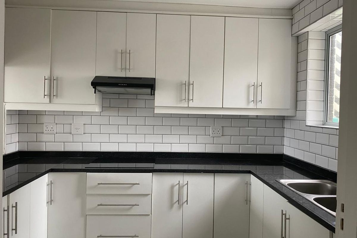Modern kitchen featuring white cabinetry, contrasting black granite countertops, subway tile backsplash, and a stainless steel double sink.